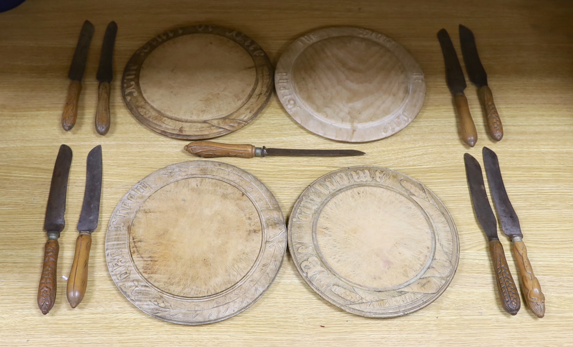 Four carved wood bread boards and a collection of knives with carved handles, boards 28cm in diameter